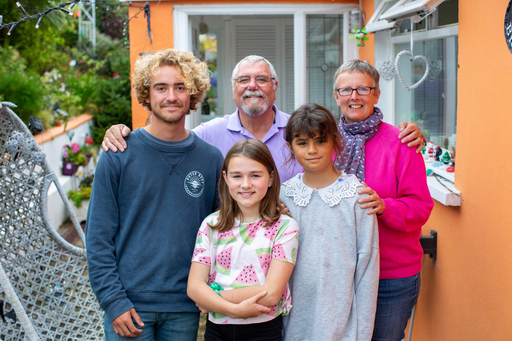 A family standing together outside of their home
