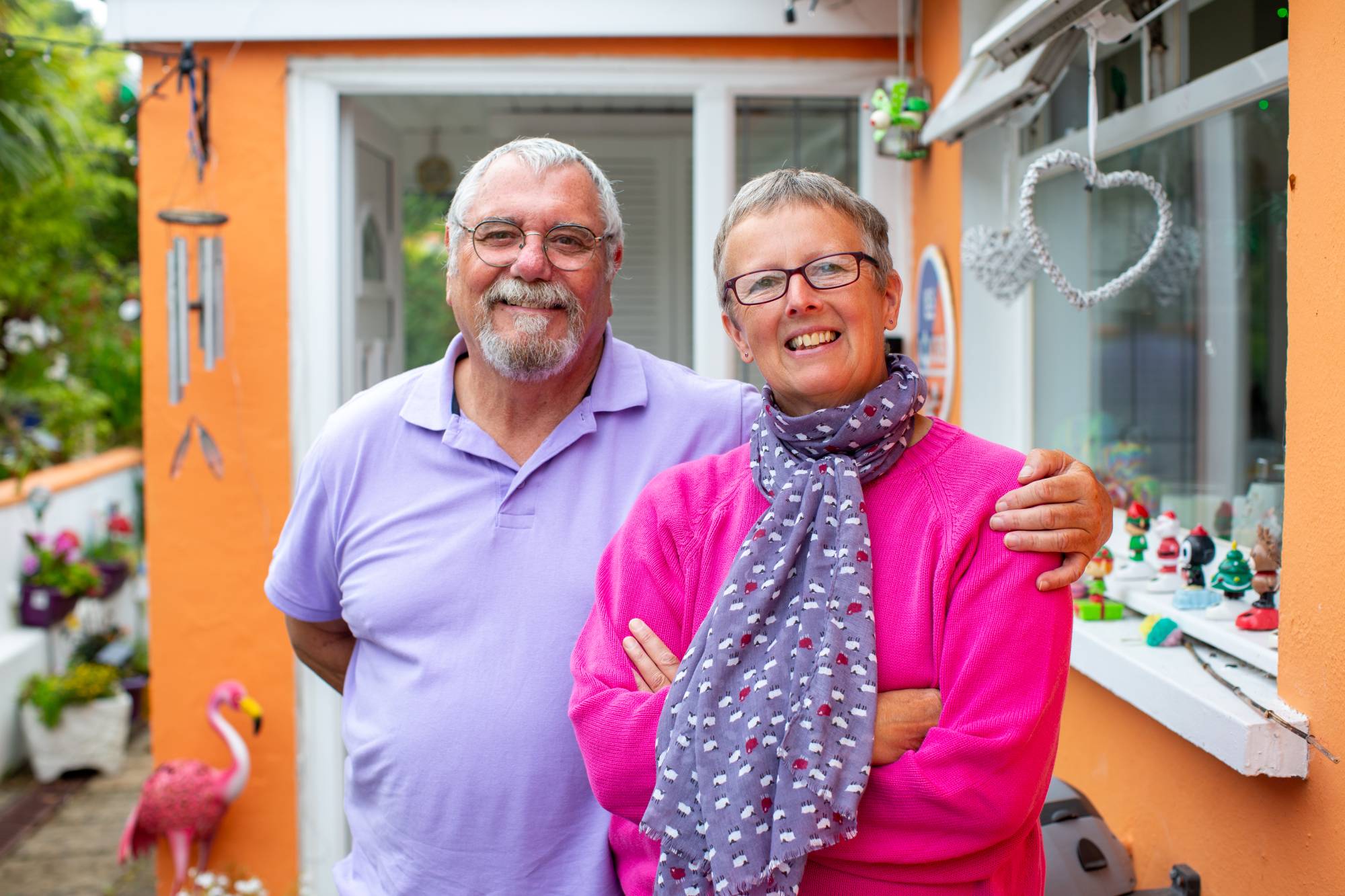 A smiling man and woman standing together outside their home