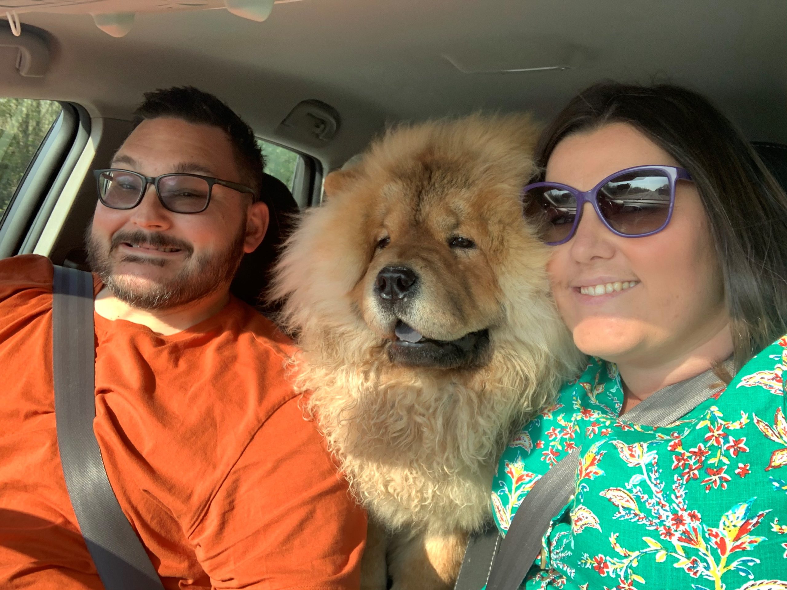 Man in orange T shirt with woman in sunglasses with dog