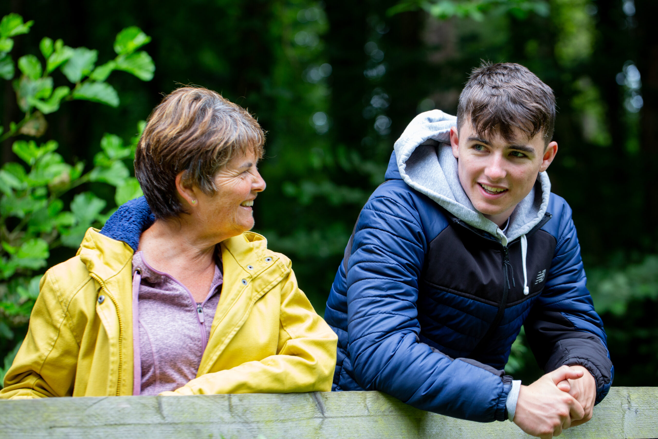 Lady and teenage boy leaning on a fence